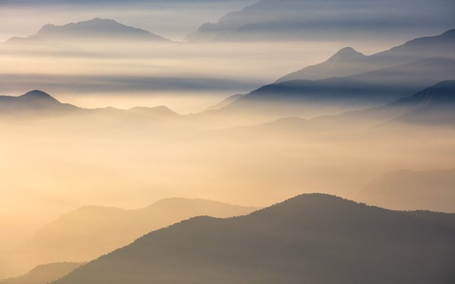 Mountains emerging from layers of fog and low clouds 
