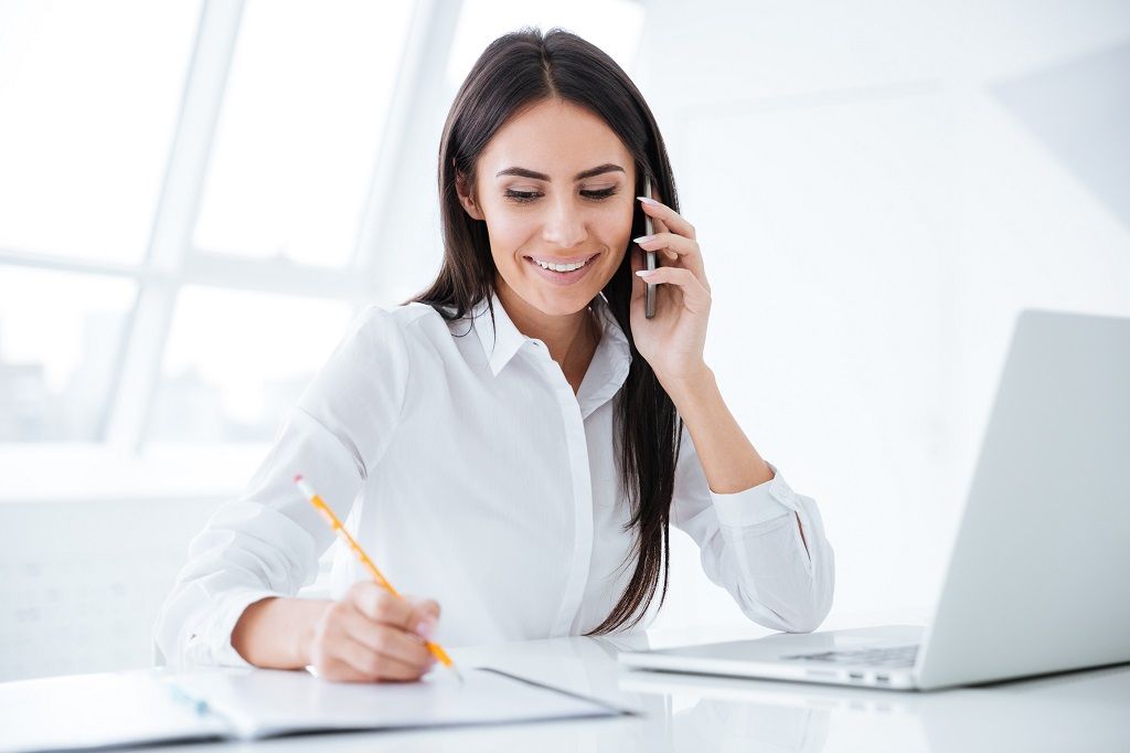 graphicstock-business-woman-talking-at-phone-and-writing-something-in-documents-by-the-table-with-laptop_SIdYvXu3g.jpg