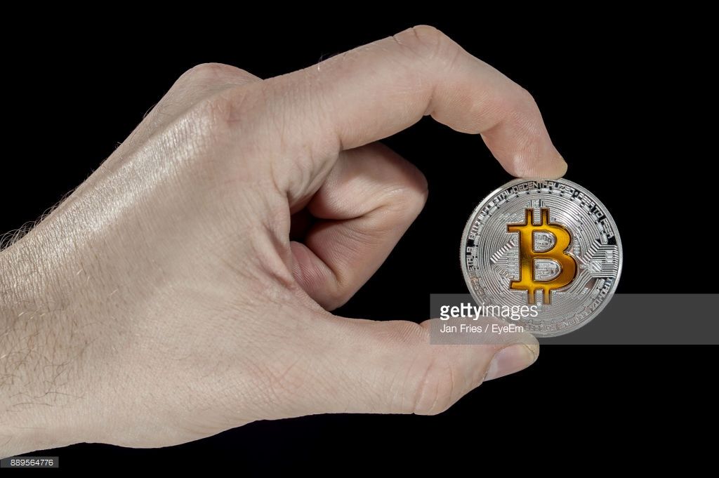 cropped-image-of-hand-holding-bitcoin-against-black-background-picture-id889564776.jpg