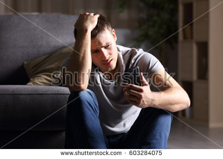 stock-photo-single-sad-man-checking-mobile-phone-sitting-on-the-floor-in-the-living-room-at-home-with-a-dark-603284075.jpg
