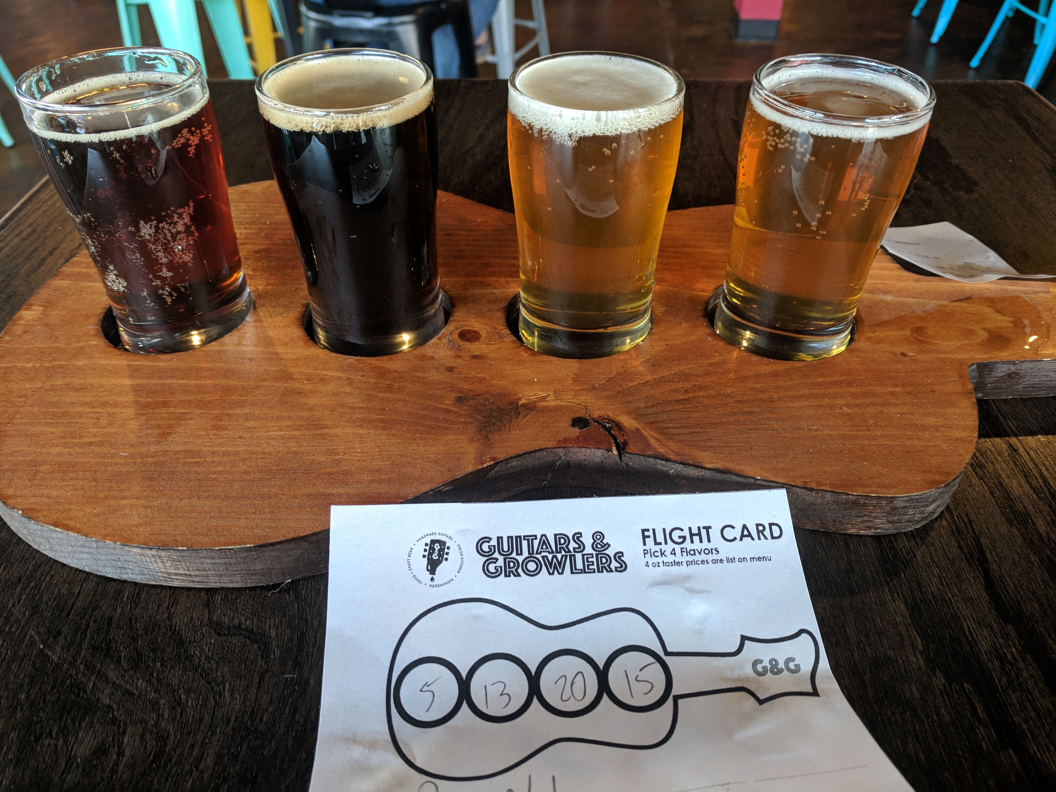 A flight of beer tasters on a guitar-shaped board