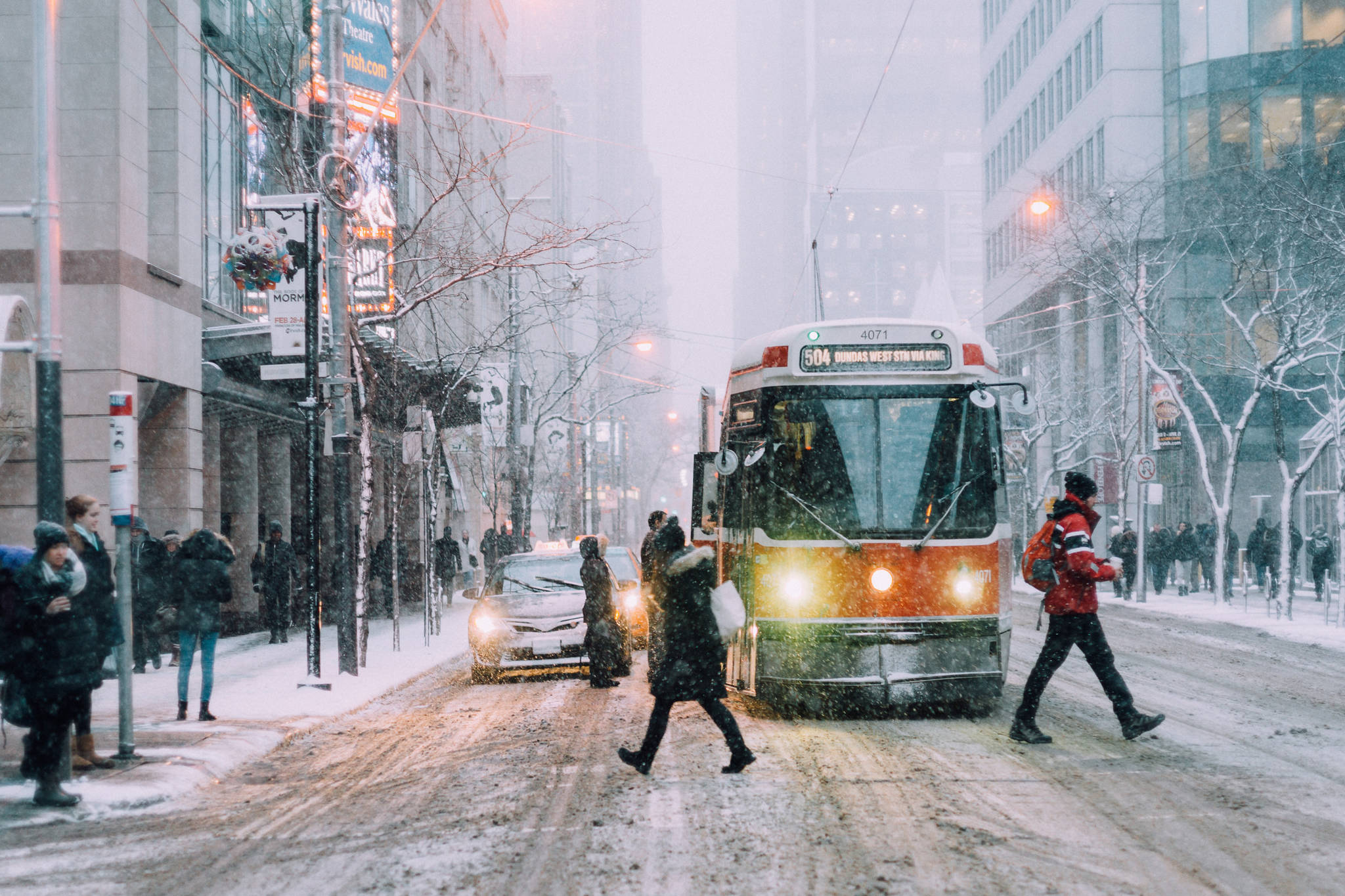 Struggles Through Snow To A Streetcar As Snow Flies Through The