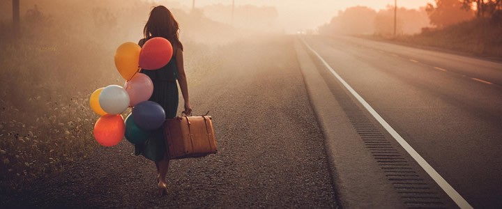 mujer-caminando-por-carretera-con-maleta-y-globos-720x300.jpg