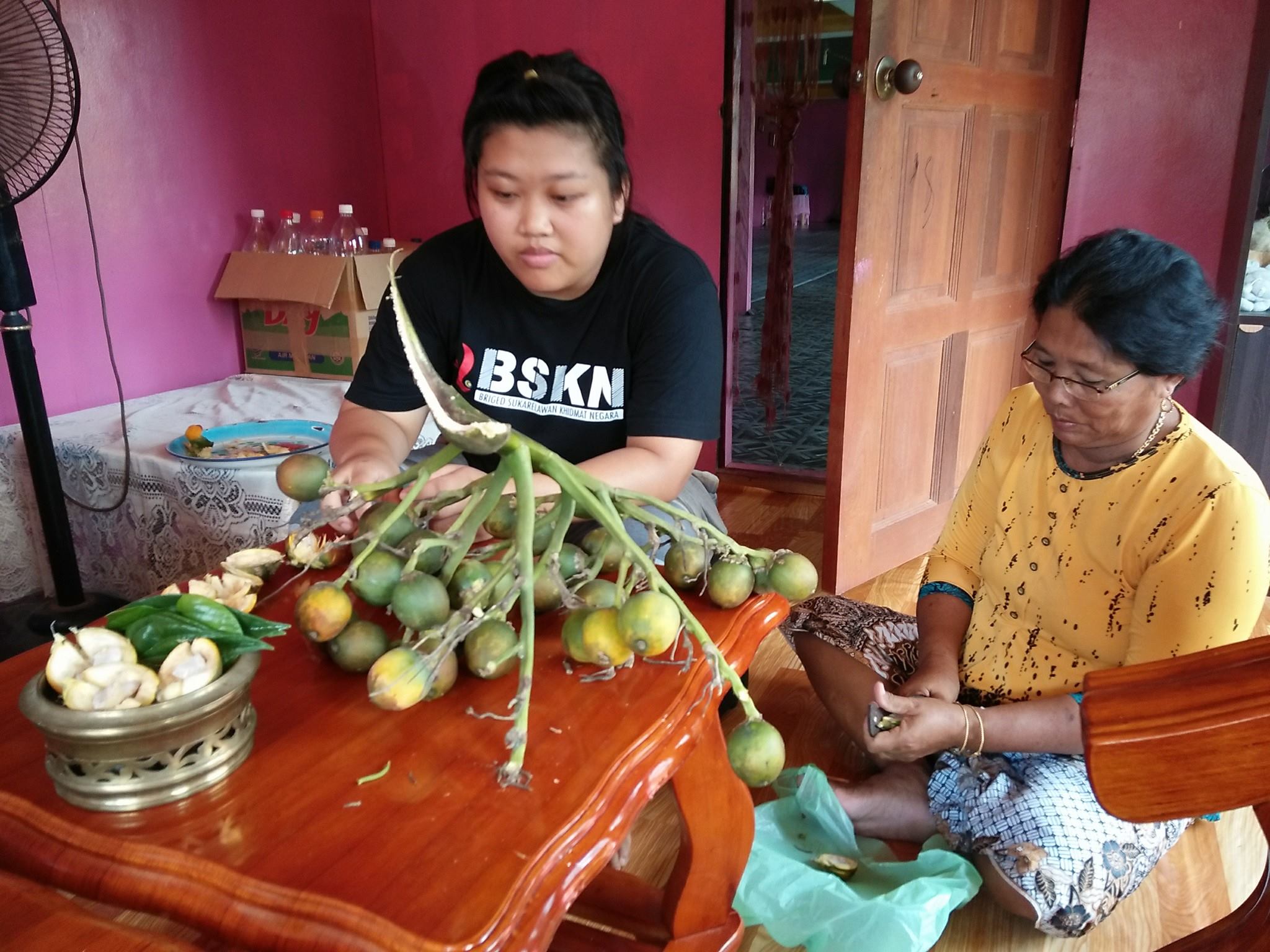 Mazinah Elli peeling the pinang nuts while her grand-daughter Nurul by her side..jpg