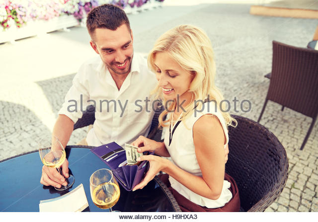 happy-couple-with-wallet-paying-bill-at-restaurant-h9hxa3.jpg