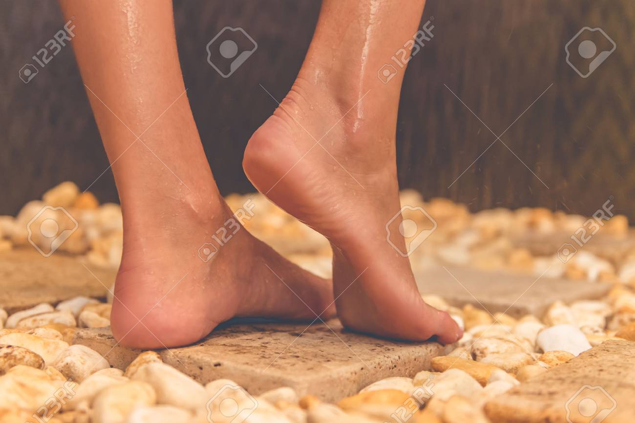 63888490-beautiful-feet-of-young-woman-standing-on-stones-while-taking-shower-in-bathroom.jpg