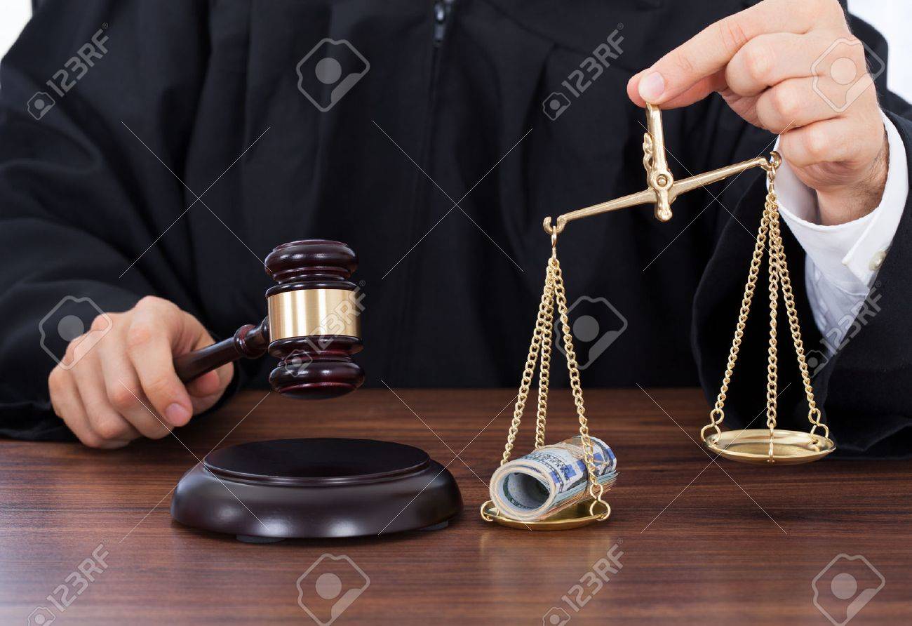 29897417-midsection-of-male-judge-striking-gavel-while-holding-scale-with-money-in-courtroom.jpg