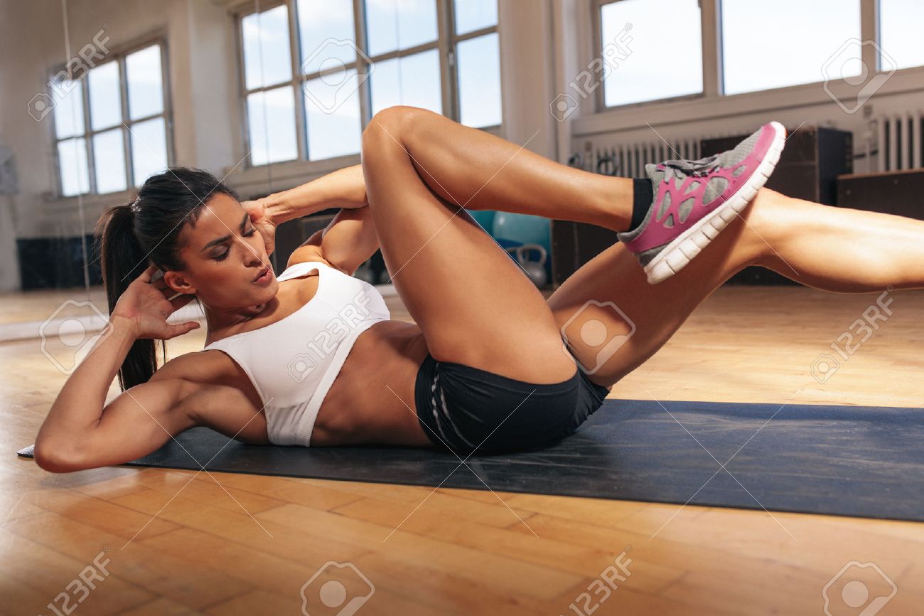 46801299-young-fit-woman-exercising-in-a-gym-lying-on-mat-doing-leg-raising-and-twisting-exercises-young-attr.jpg