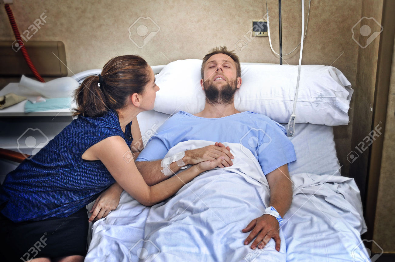 42897387-young-sick-man-lying-in-bed-at-hospital-room-after-suffering-accident-having-his-worried-and-caring--Stock-Photo.jpg