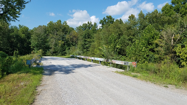 A  graffiti railed  bridge on a gravel country road