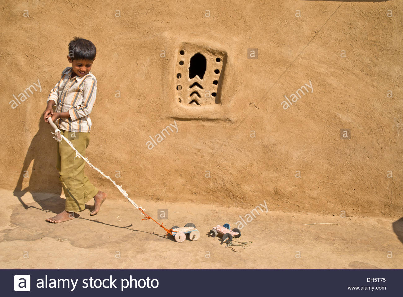 boy-playing-with-a-home-made-toy-cars-outside-a-mud-house-wste-thar-DH5T75.jpg