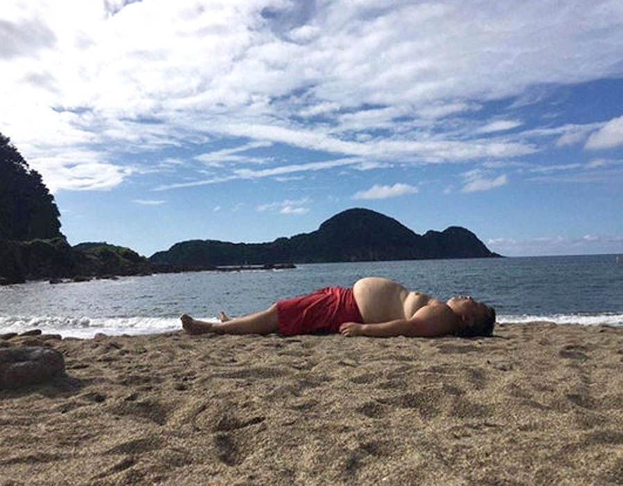 a person lying on beach resembles with a cliff in background.jpg