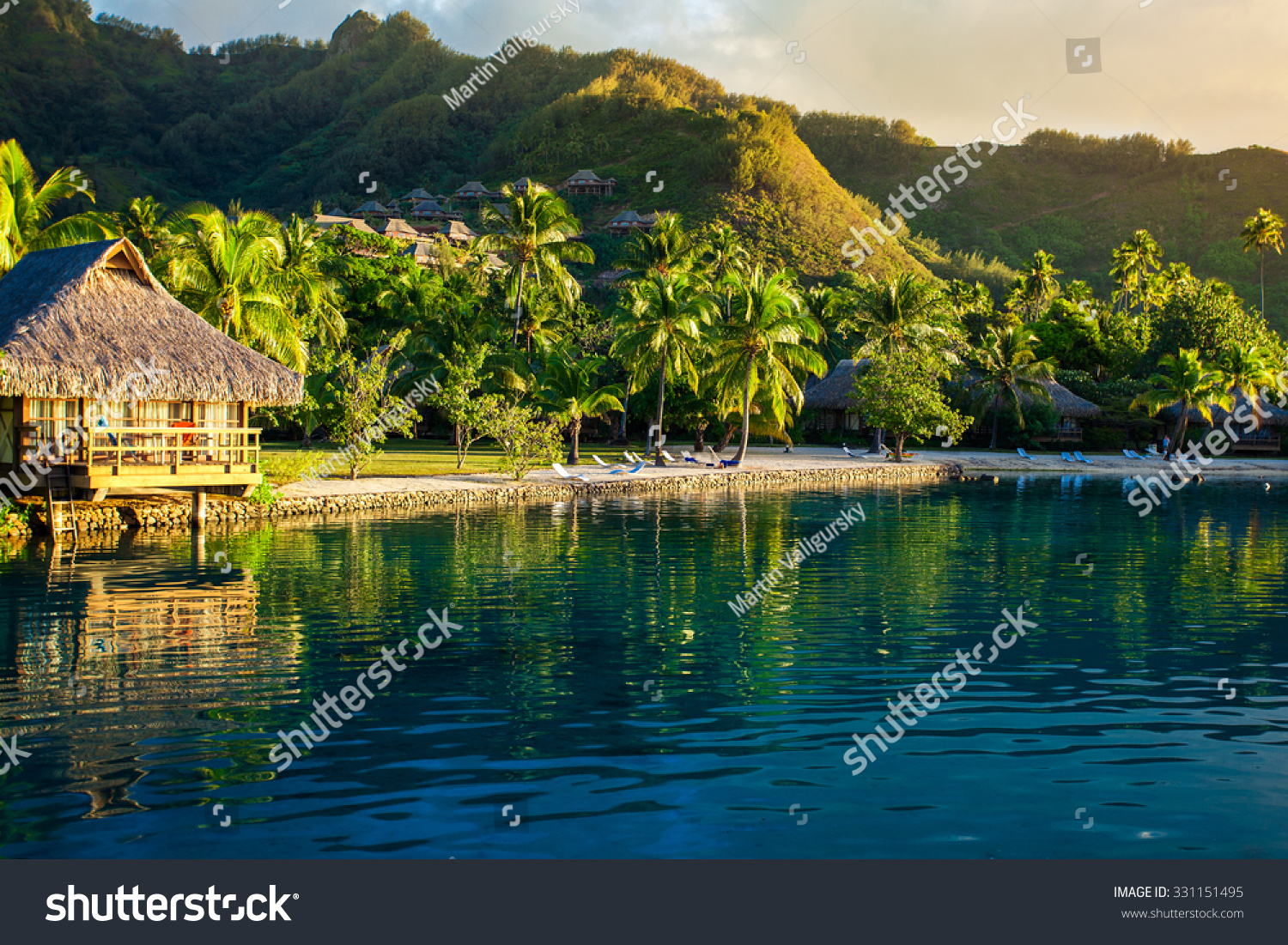 stock-photo-villas-in-a-tropical-resort-and-with-palm-trees-reflected-in-the-ocean-during-sunset-331151495.jpg