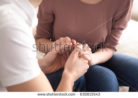 stock-photo-close-up-view-of-man-holding-hands-of-a-woman-sitting-on-sofa-indoors-love-confession-or-marriage-630815543.jpg