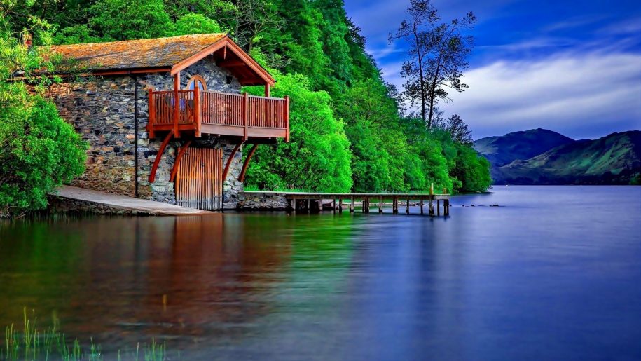 Stone-house-on-the-shore-of-the-lake-wooden-terrace-wooden-dock-port-for-boats-green-forest-lake-mountains-sky-with-white-clouds-915x515.jpg
