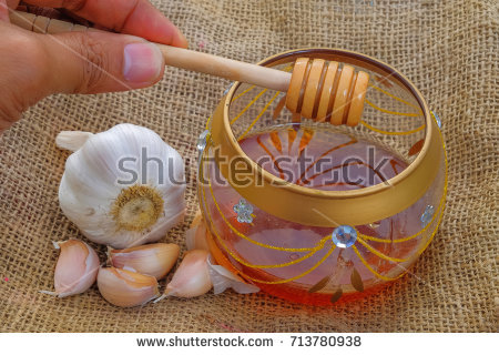 stock-photo-close-up-of-garlic-and-jar-with-honey-and-dipper-on-jute-healthy-eating-713780938.jpg
