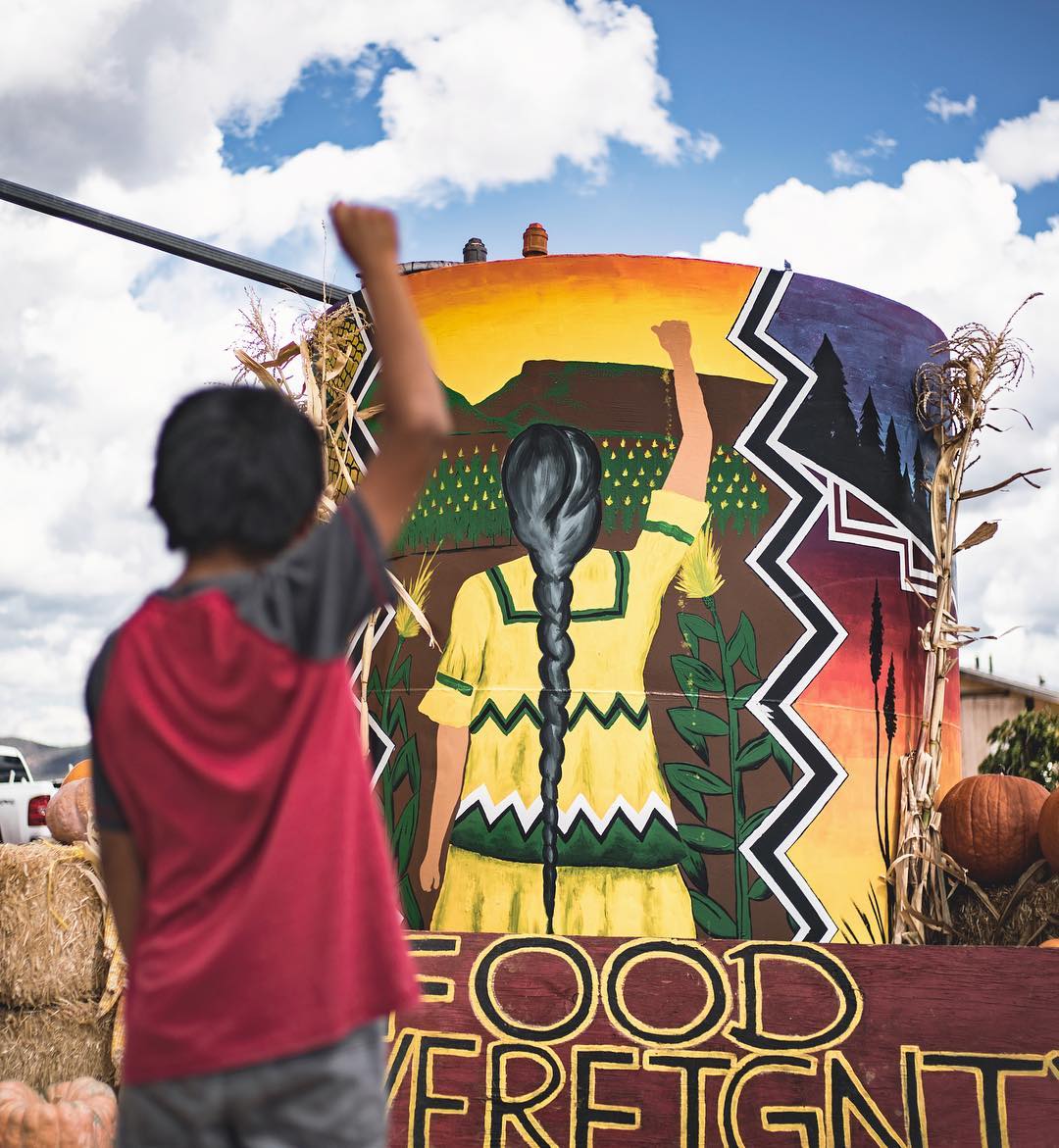 An Apache boy mimics a mural at a recent harvest festival on the White Mountain .jpg