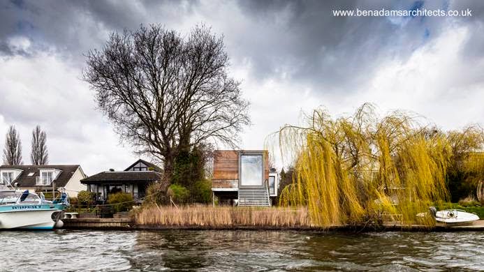 La casa elevada despegada de las vecinas con su amplia ventana vista desde el río.jpg