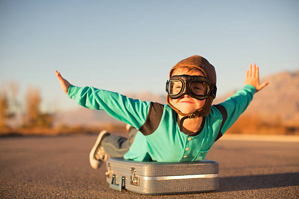 young-boy-with-goggles-imagines-flying-on-suitcase-picture-id597927618.jpg
