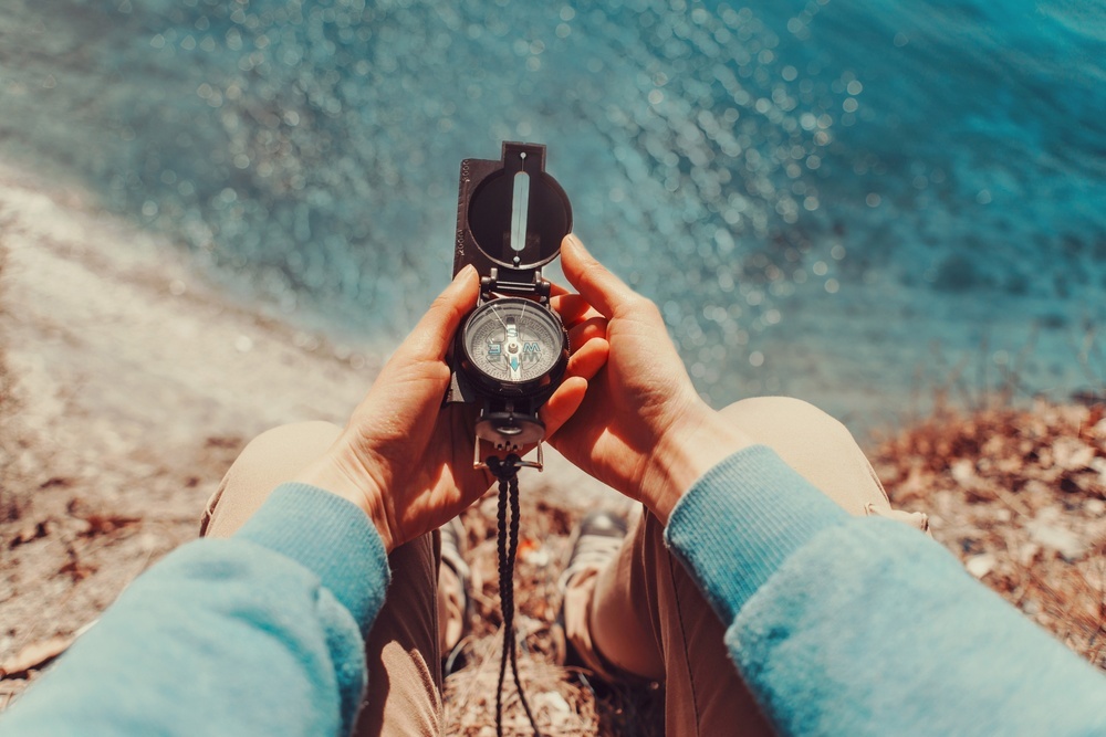 traveler-woman-searching-direction-with-a-compass-on-coastline-near-the-sea-point-of-view-shot.jpg
