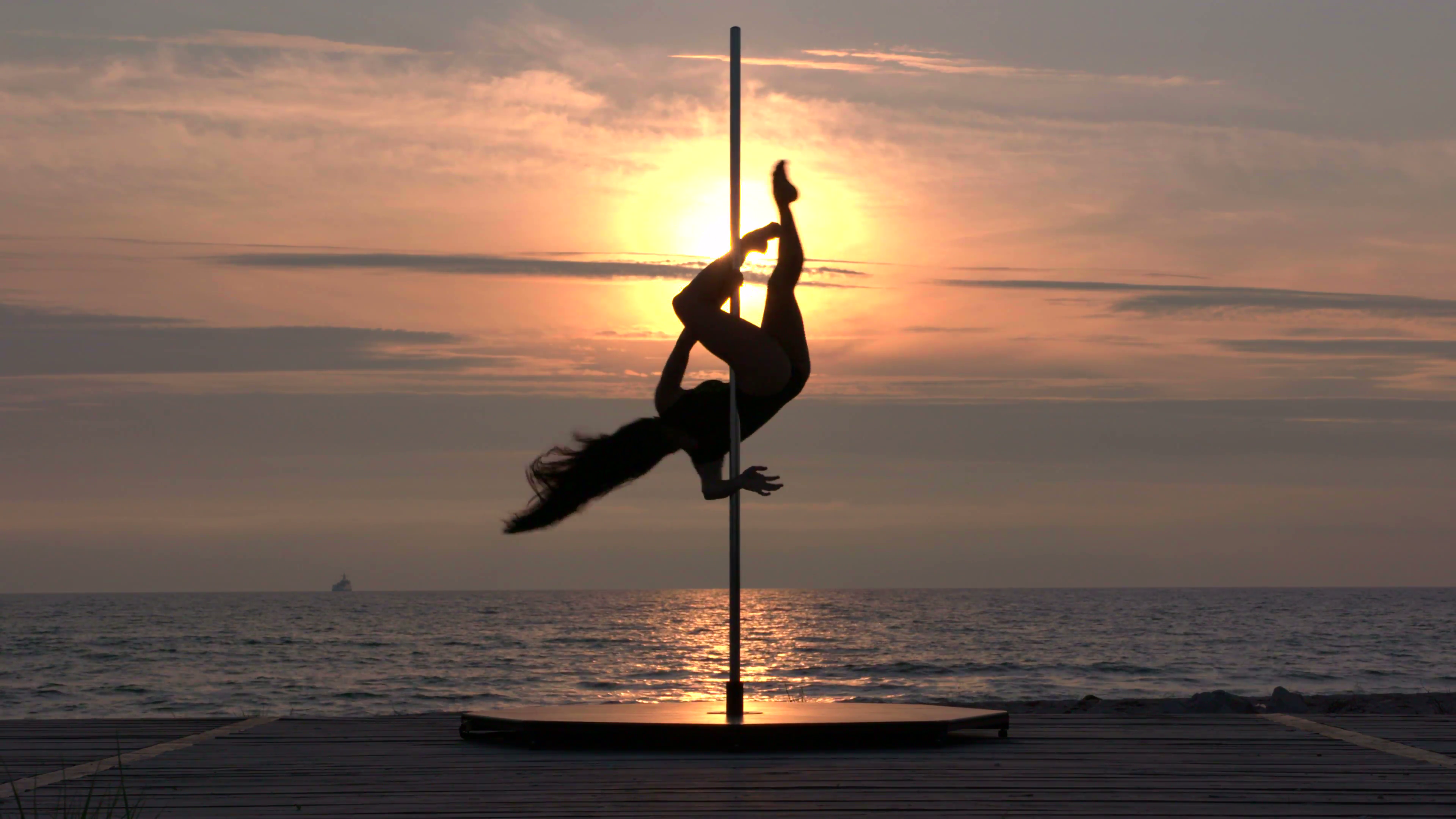 spinning-silhouette-of-girl-pole-dancer-against-the-glowing-sun-setting-in-the-sky-professional-poledancer-performing-tricks-and-spins-during-fitness-pole-dance-on-the-beach-part_s7_hwztpg-1i__F0007.png