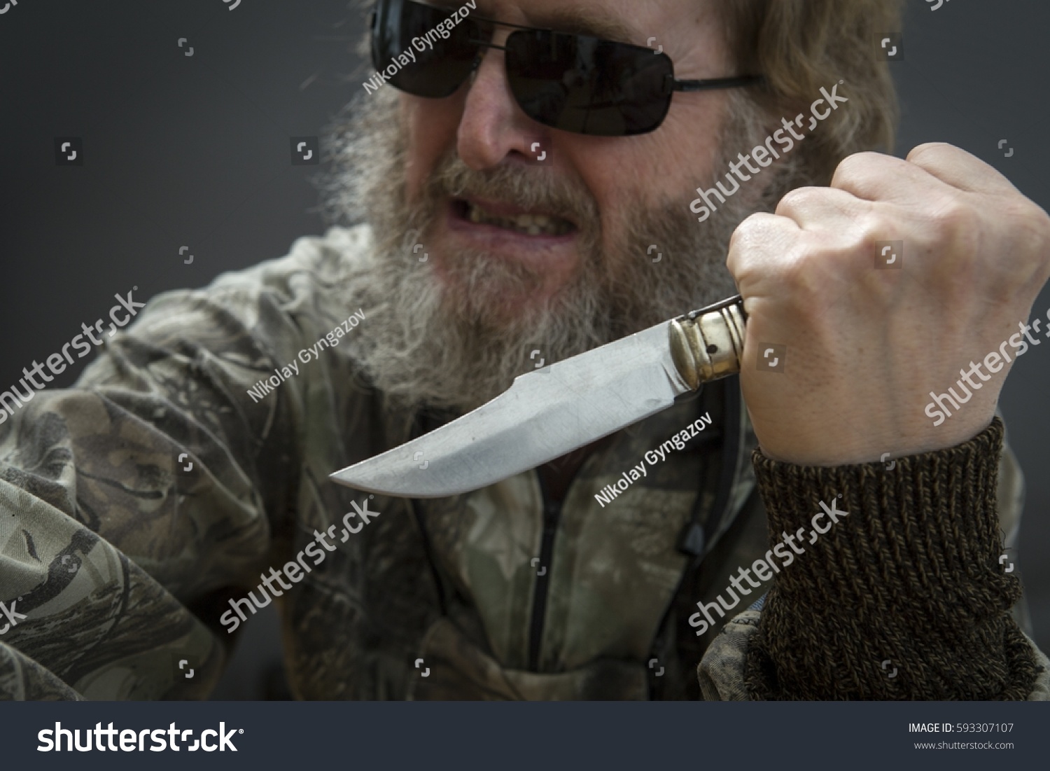 stock-photo-the-knife-in-the-hand-of-a-man-with-a-beard-against-a-dark-back.jpg