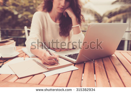 stock-photo-woman-working-on-computer-and-writing-down-her-thoughts-315382934.jpg