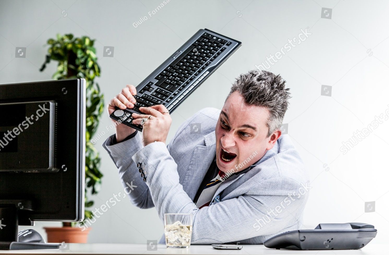 stock-photo-office-worker-destroying-his-computer-by-smashing-the-keyboard-over-the-screen-446107957.jpg
