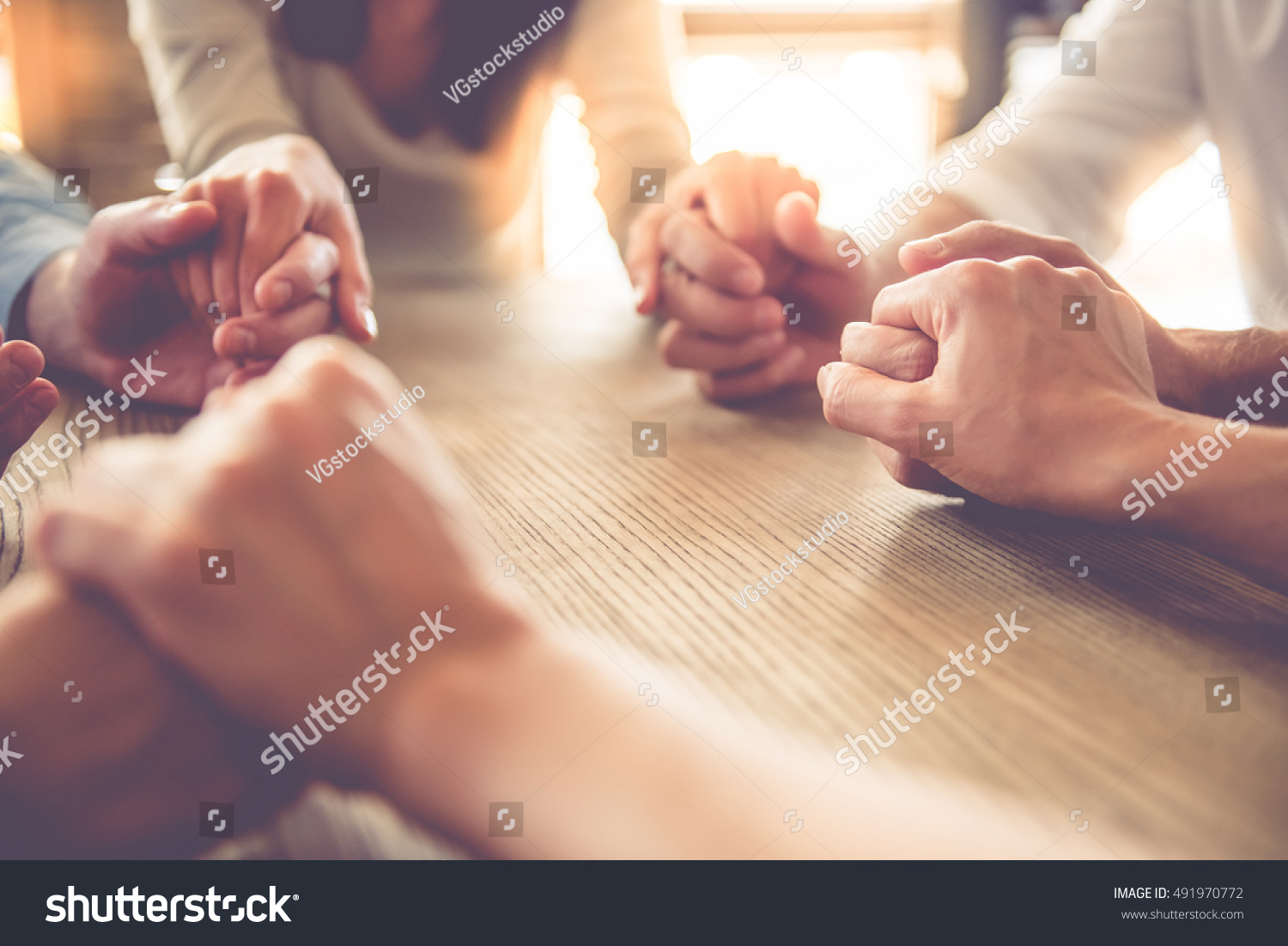 stock-photo-cropped-image-of-beautiful-business-team-holding-hands-and-praying-while-sitting-in-office-491970772.jpg