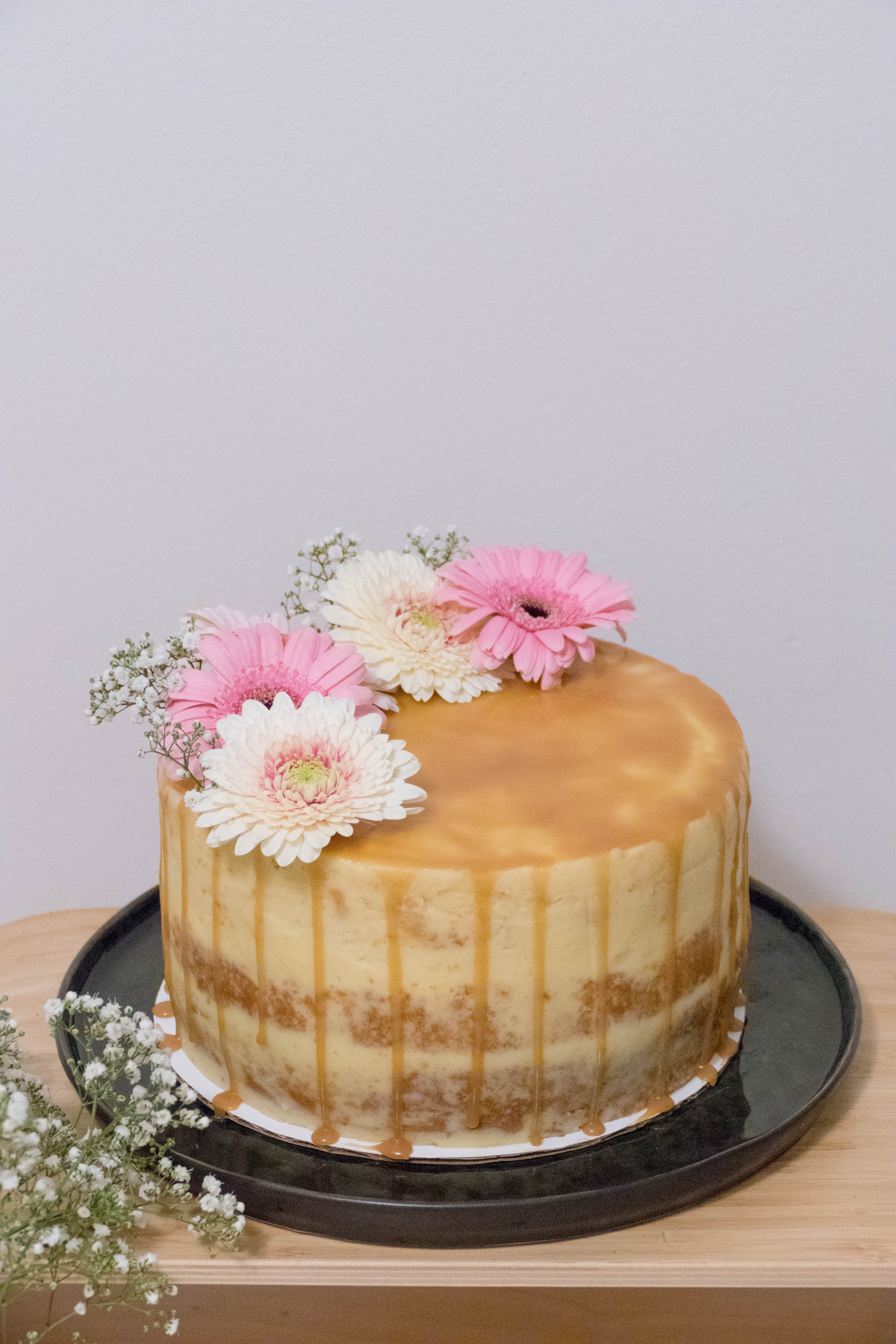 Honey cake with milk cream, caramel, almonds and a cup of coffee on a gray  wooden background Stock Photo by uladzimirz