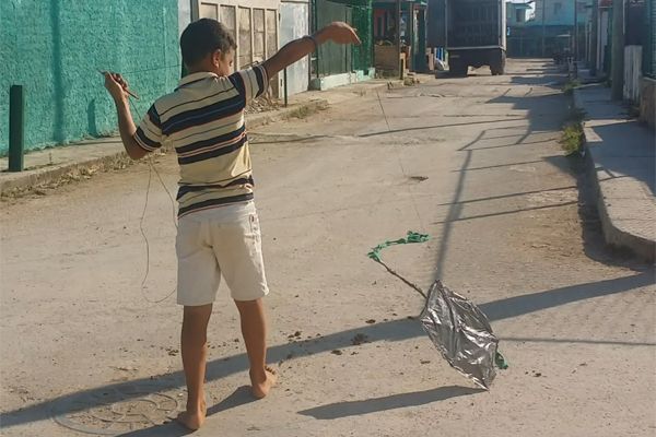 niño tratando de volar papalote en la calle.jpg