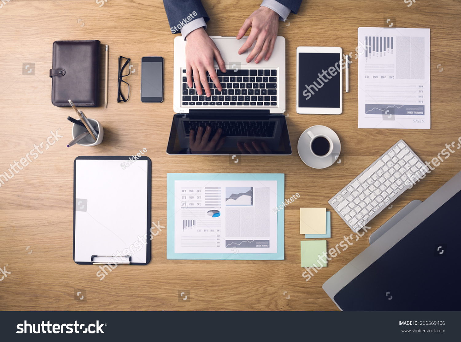 stock-photo-businessman-working-on-a-laptop-at-office-desk-with-paperwork-and-other-objects-around-top-view-266569406 (1).jpg