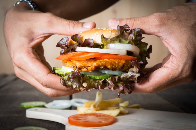 man-holds-burger-with-hands-and-potato-chip_1150-1863.jpg