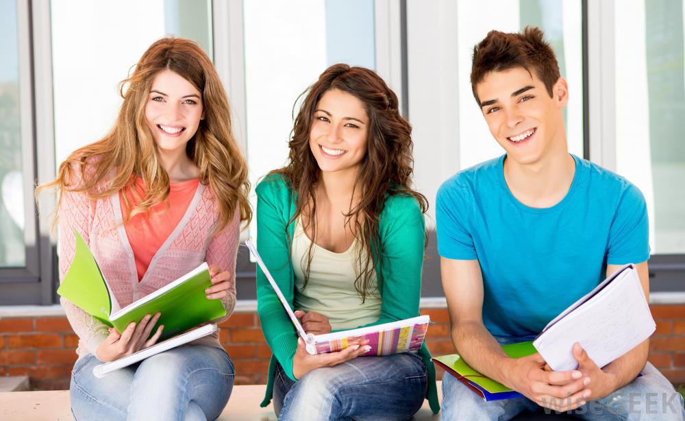 two-girls-and-one-boy-student-smiling-with-notebooks.jpg