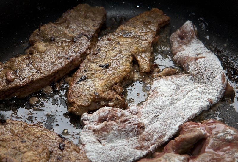 Жареная говяжья печень на сковороде. Печень жареная куском. Печень говяжья жареная с луком на сковороде большими кусками. Печень кусками жареная на сковороде. Обжаренный кусок печенки.